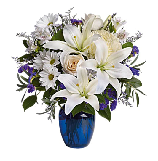 White lilies roses and chrysanthemums in a cobalt blue glass vase