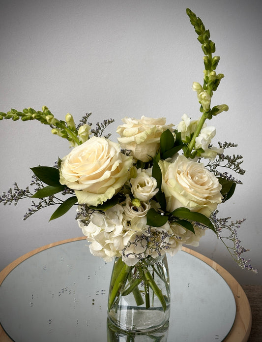 Soft and Pretty floral arrangement with white roses hydrangea and snapdragons in a clear glass vase