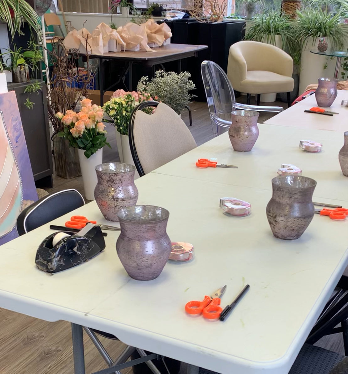 a table set up for a flower arranging workshop with pretty vases tools and fresh flowers 