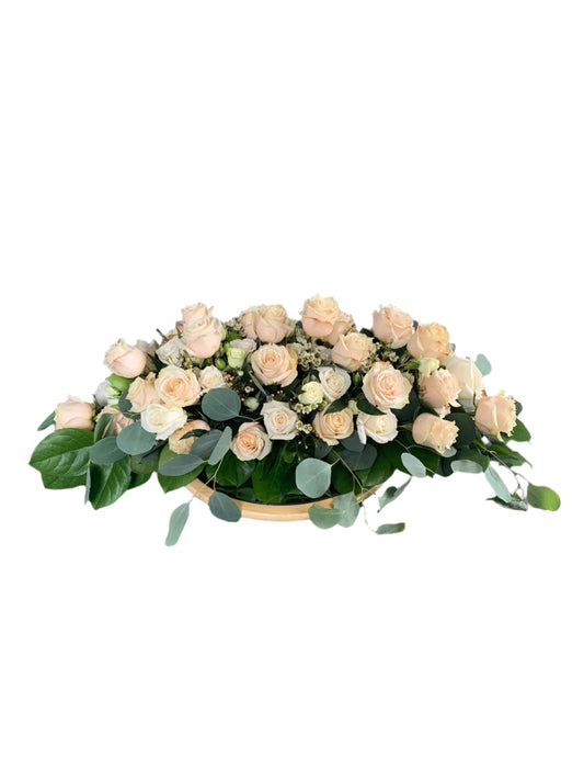 Long and low floral centrepiece with roses, lisianthus and waxflower